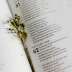 A close-up of an open Bible page with scripture and delicate white flowers.
