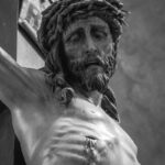 Black and white close-up of a crucifix sculpture conveying religious devotion.